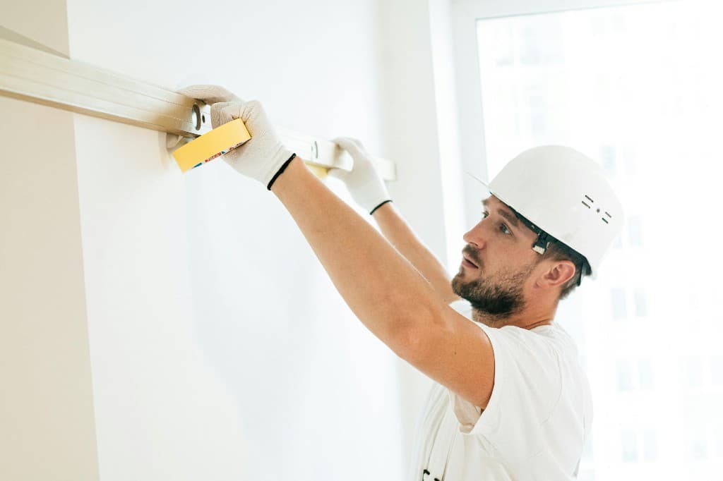 Worker preparing wall with level and painter's tape