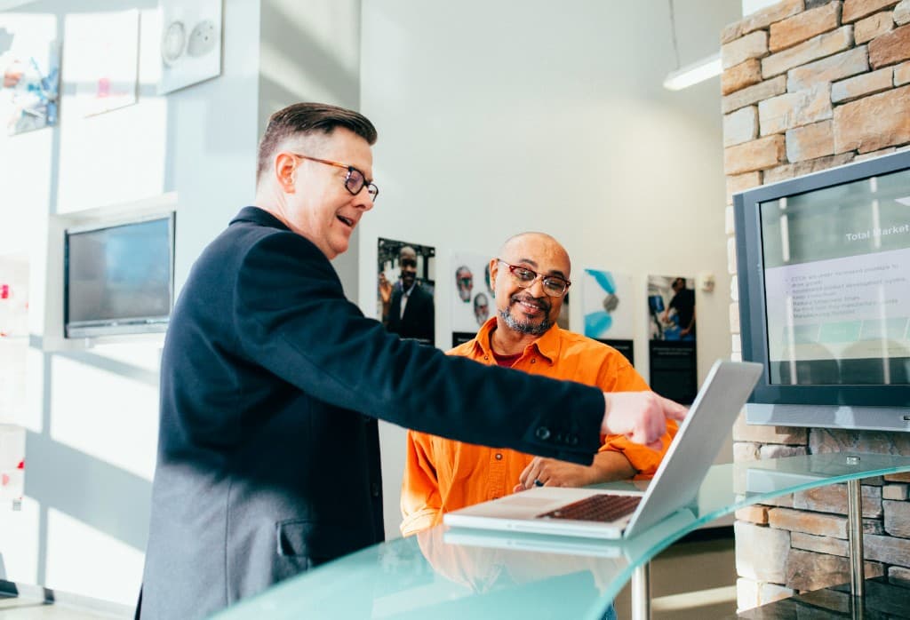 Two professionals collaborating over laptop in office